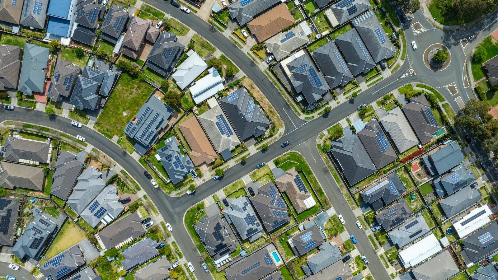 Aerial view of a planned suburban neighborhood with houses, streets, and rooftop solar panels